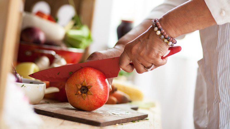 Female hand cutting pomegranate