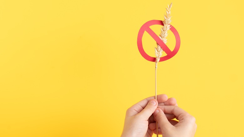 Child hands holding stalk of wheat surrounded by gluten free symbol