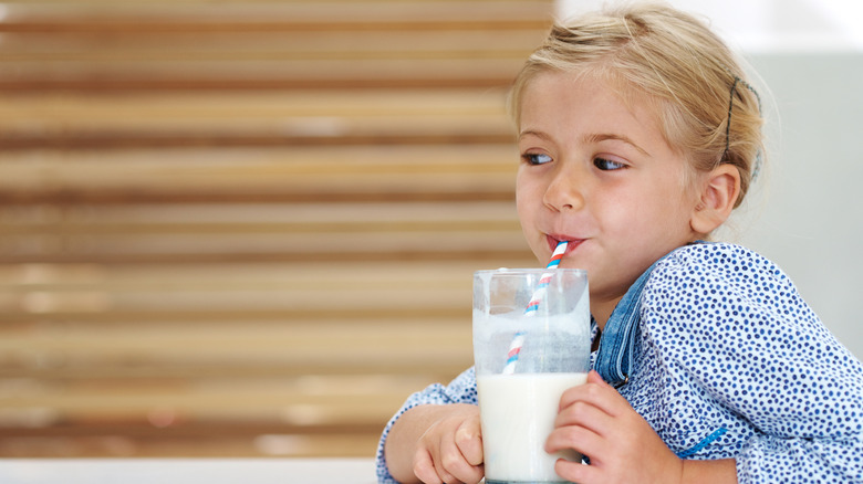 young girl drinks milk from a glass