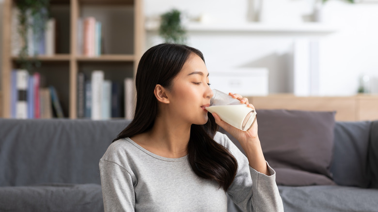 young woman drinks glass of milk