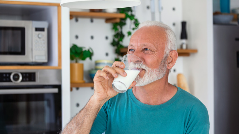 older man drinks glass of milk