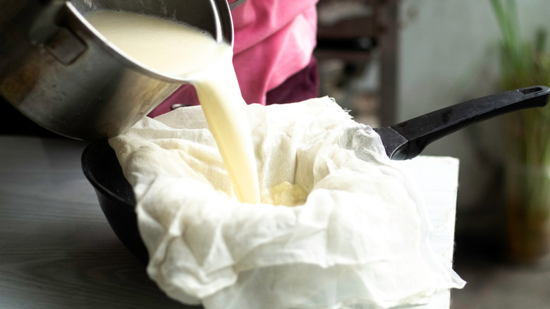 pouring strained soy milk over cloth