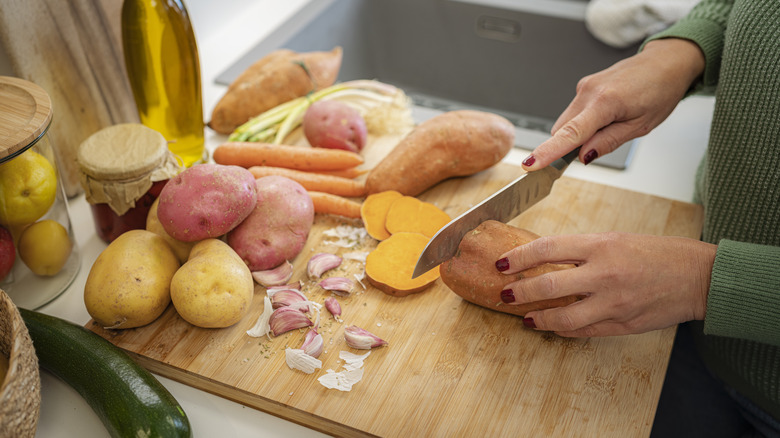 person chopping sweet potato and white potato