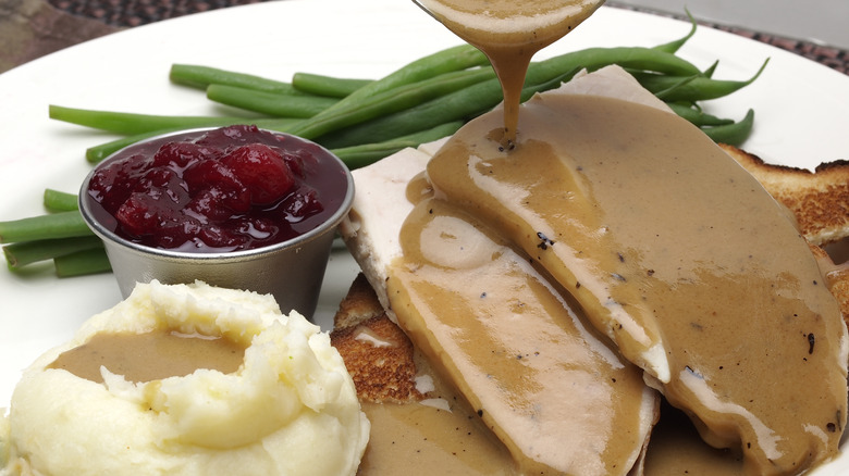 Person dowsing slices of turkey in gravy