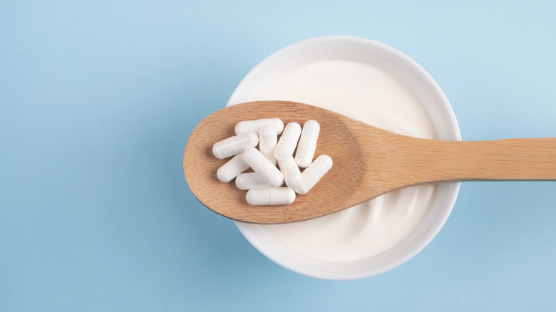 yogurt bowl and spoonful of probiotic capsules