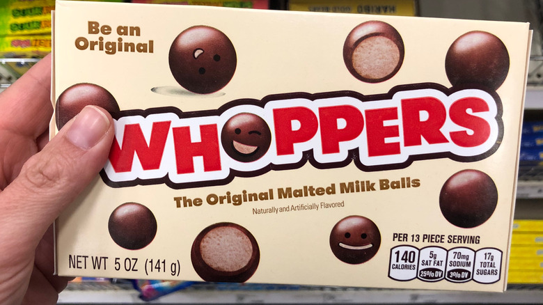 Hand holding a box of Whoppers candy