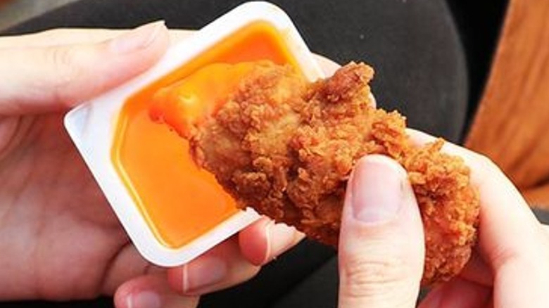 hands dipping nugget in sauce