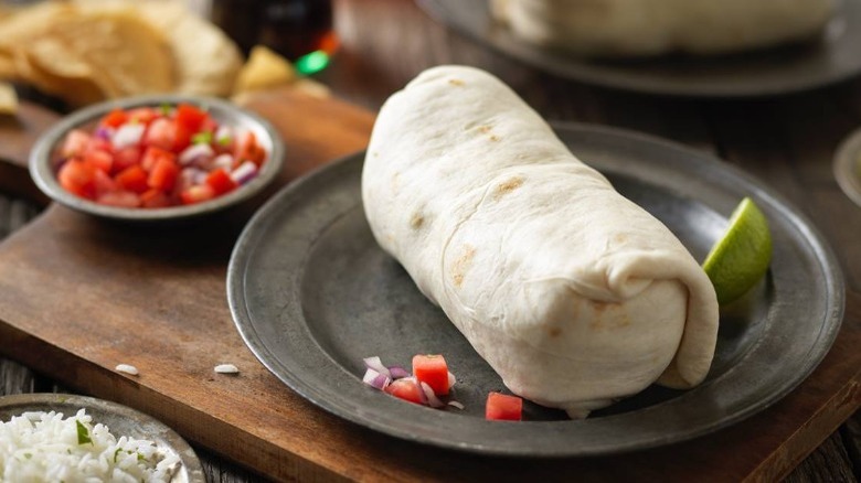 Qdoba's Grilled Adobo Chicken Burrito with pico de gallo on a black plate 