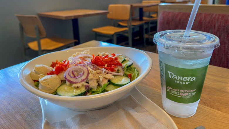 Salad in a bowl and water in a cup from Panera Bread