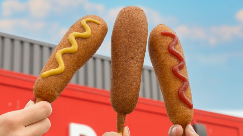 three corn dogs with sauces