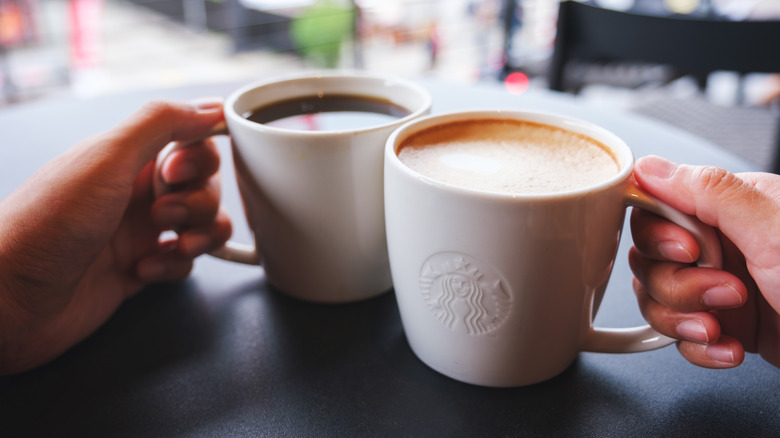 hands holding two Starbucks coffee mugs