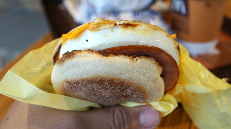 hand holding Egg McMuffin sandwich