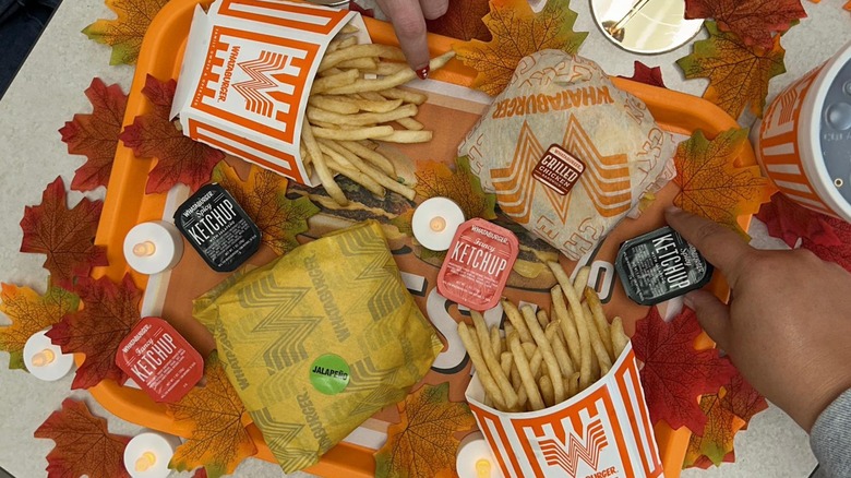 Whataburger fries and a meal sit on a table with leaves and candles.