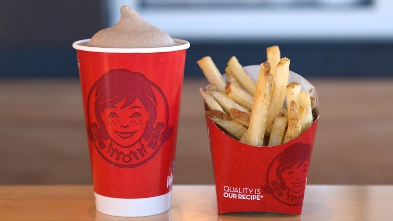 A Wendy's Frosty and an order of fries sit side by side on a table.d out on a table.