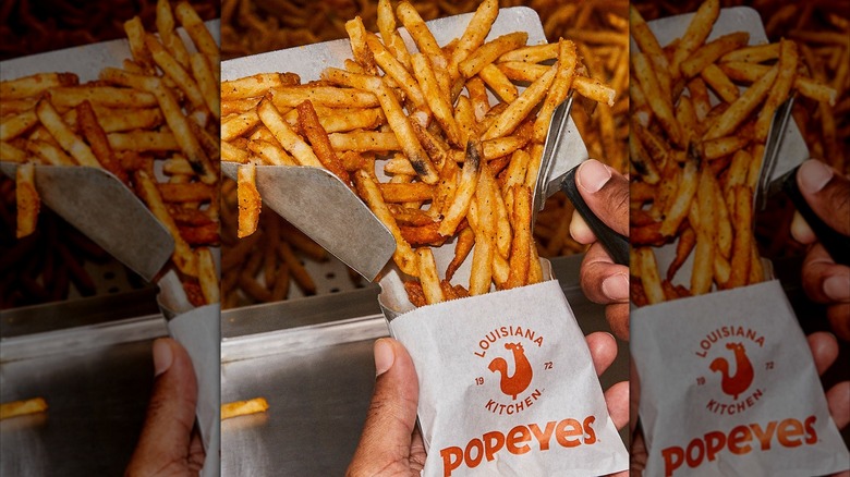 Popeyes fries are being scooped into a bag.