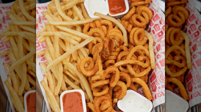 Jack in the Box regular and curly fries are displayed on a platter with sauces.