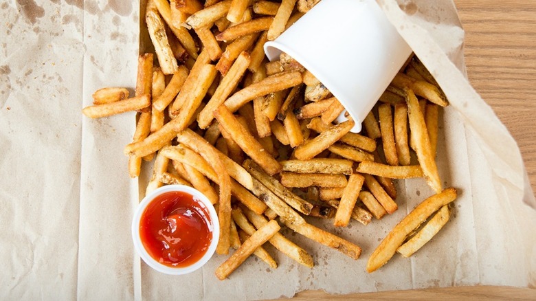 Five Guys fries are spread on a napkin with a side of ketchup.