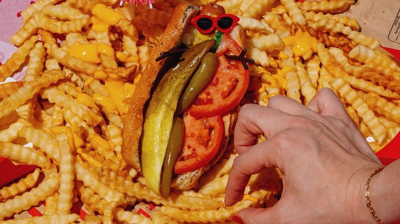 Portillo's fries are spread on a table with a Chicago hot dog.