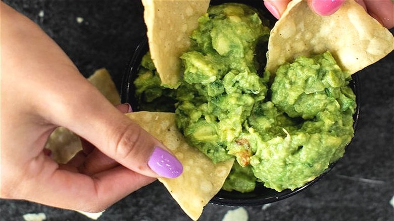 People dipping chips in guacamole