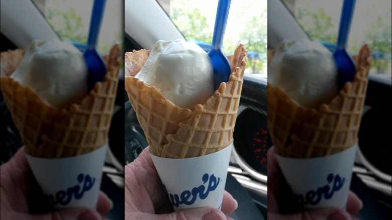 Person holding Culver's Vanilla Waffle Cone with a spoon