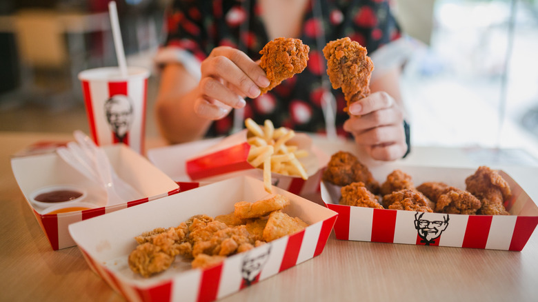 KFC fried chicken in bucket hands holding drumsticks