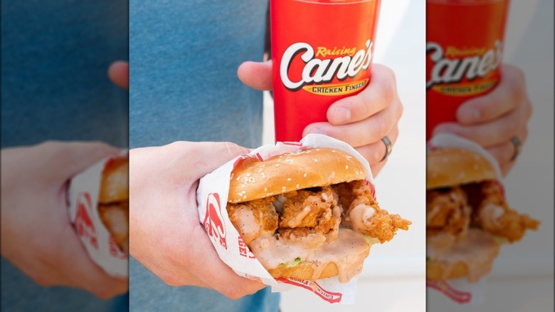 Hand holding chicken sandwich and drink