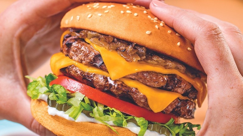 hands holding double cheeseburger