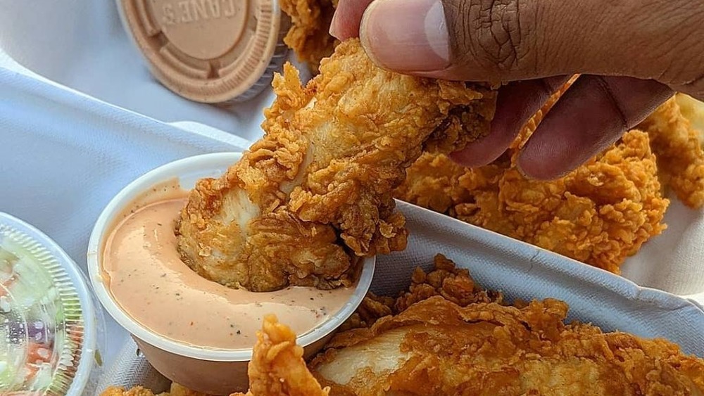 Person dipping chicken tender in dip