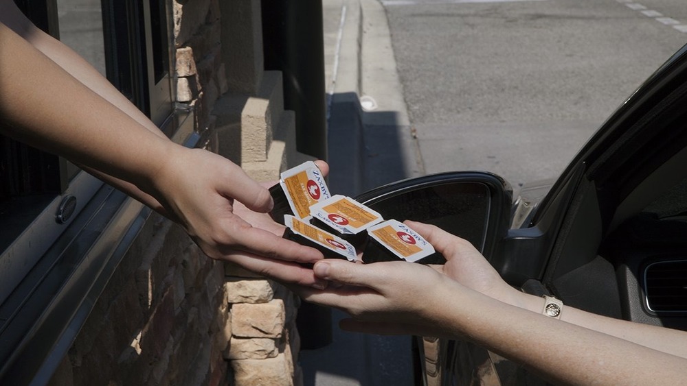 Employee handing sauce to drive-thru customer