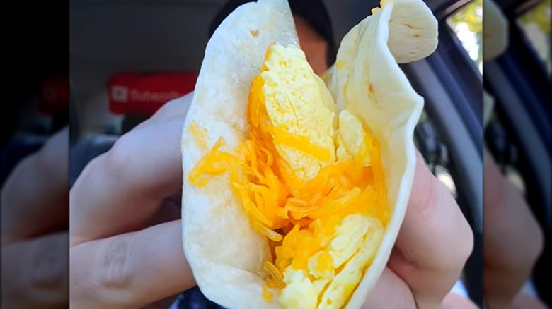Hands holding del taco egg and cheese