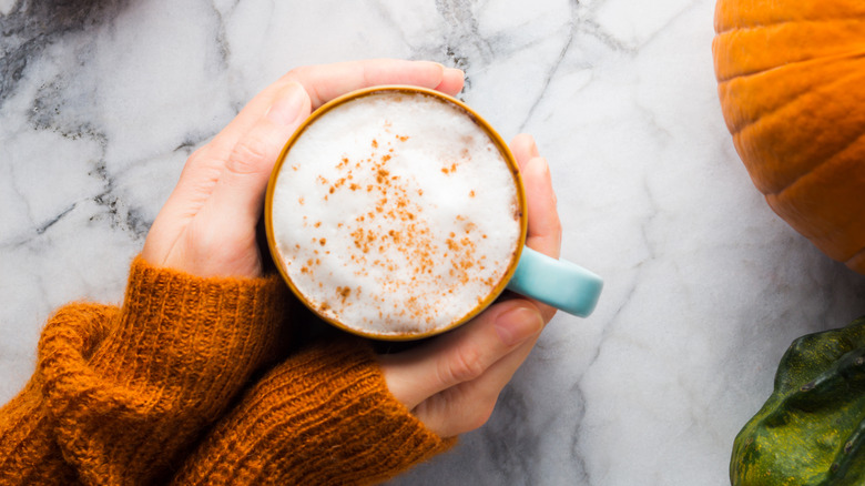 Woman holding mug of pumpkin spice latte