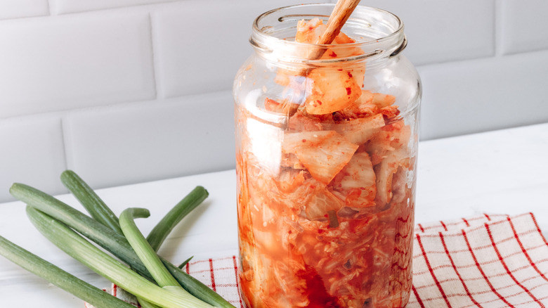 jar of kimchi with scallions on the side in a home kitchen setting