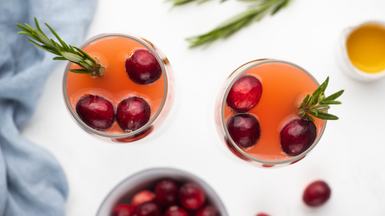 Two cranberry mimosa cocktails with fresh cranberries and rosemary