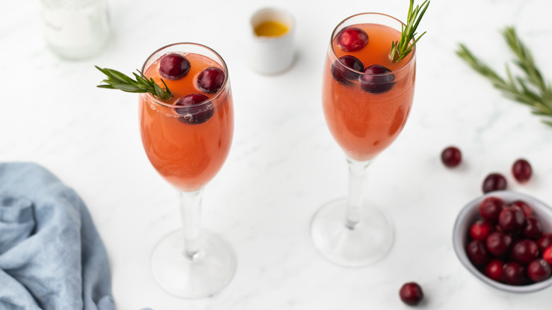 Two cranberry mimosas with fresh cranberries and rosemary