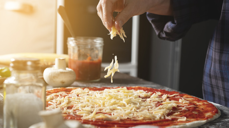 sprinkling cheese on homemade pizza