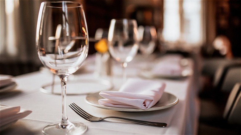 Fine dining table set with plates, napkins, silverware and wine glasses