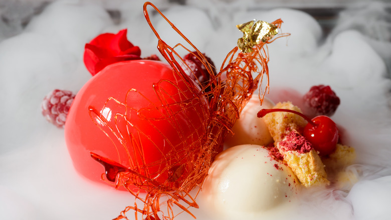 Molecular gastronomy plate featuring red and white edible spheres and dry ice smoke