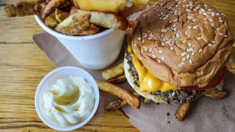 A picture of a Five Guys burger, cup of fries, and dipping mayo from above