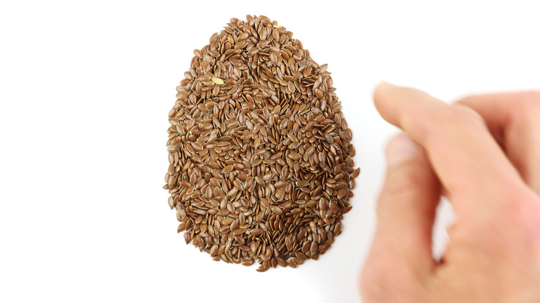 Hand arranging flax seeds in an egg shape