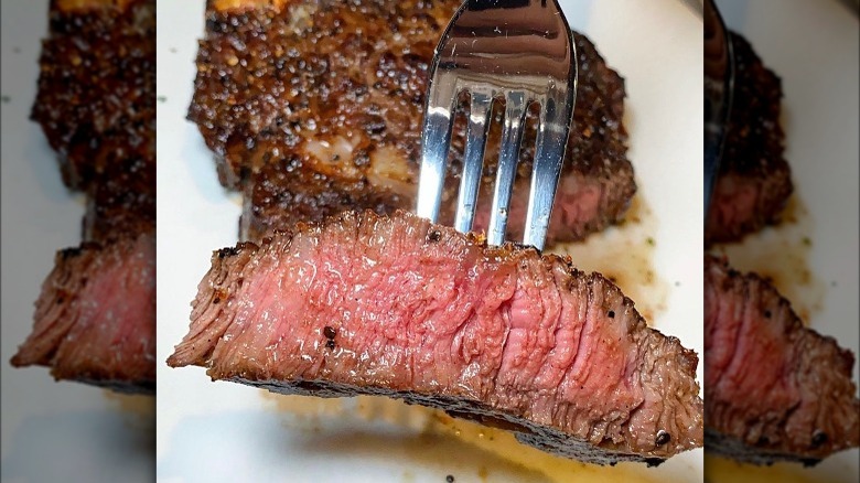 cooked piece of steak on fork