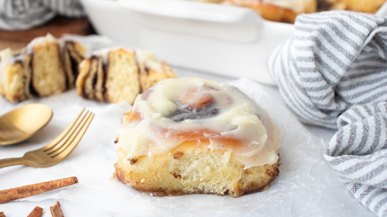 frosted cinnamon roll next to a grey-and-white-striped towel