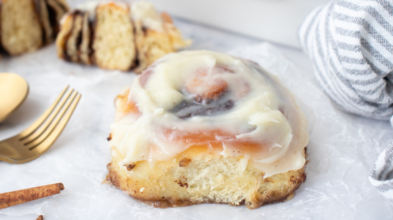 frosted cinnamon roll next to a grey-and-white-striped towel