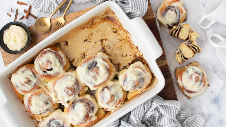 frosted cinnamon rolls in a white pan