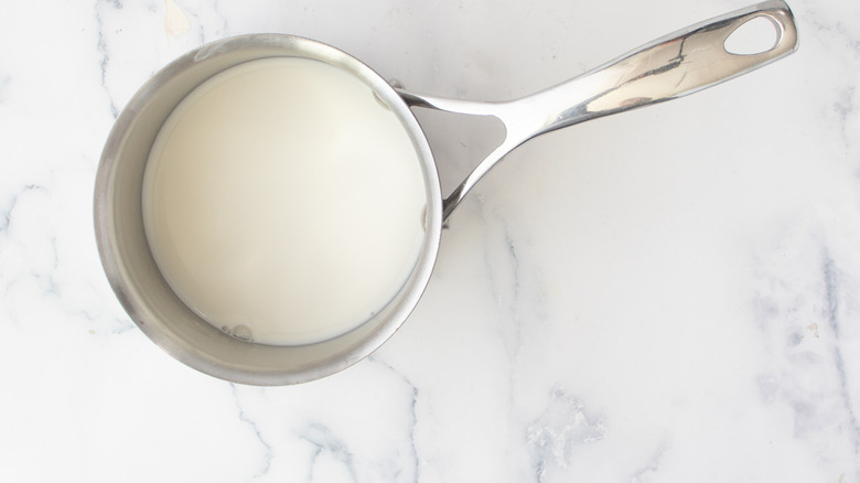 milk in a metal pot on a white countertop