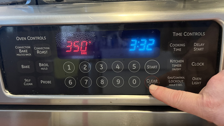 hand touching oven temperature gauge