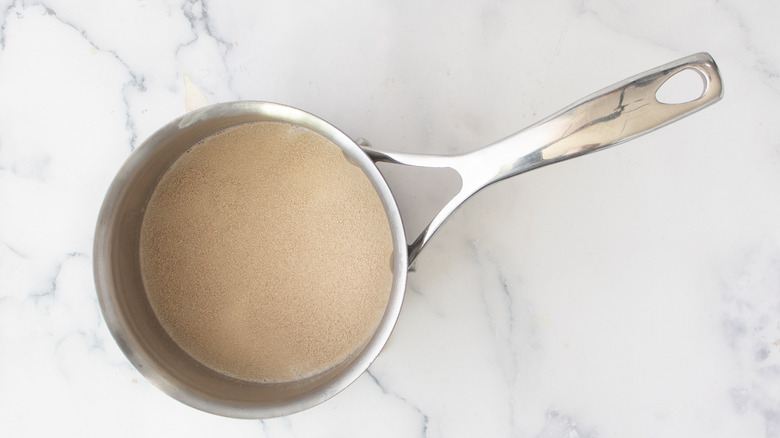 tan liquid in a metal pot on a white countertop