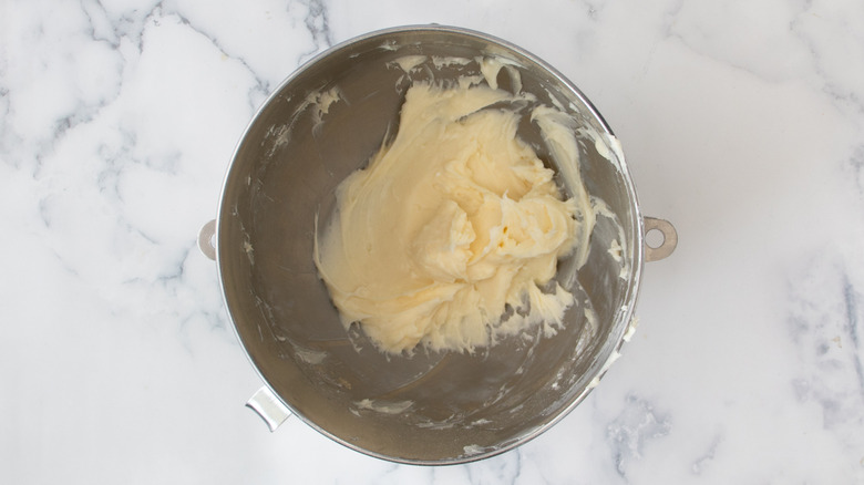 yellowish frosting in a metal bowl on a white countertop