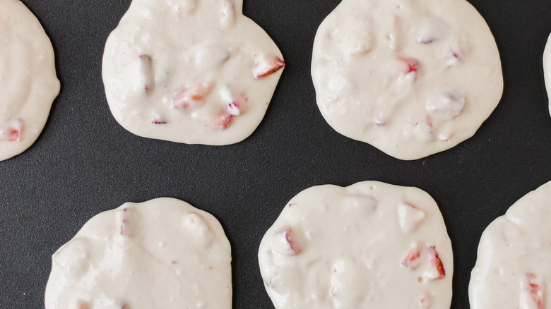 Uncooked homemade strawberry pancakes on a griddle