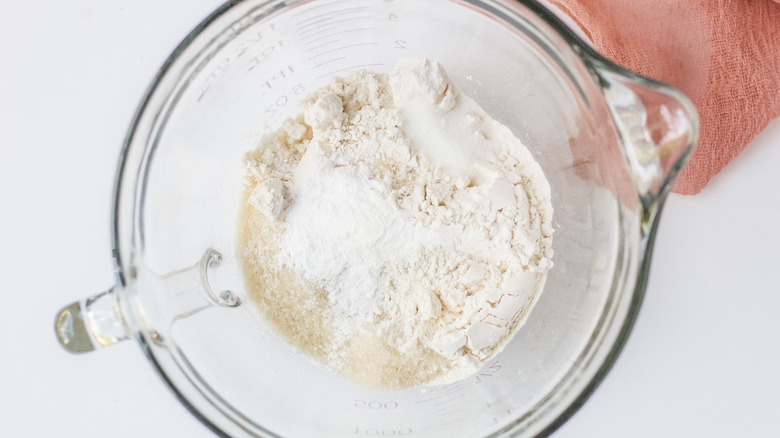 Overhead shot of flour, sugar, baking powder and salt in a glass measuring cup