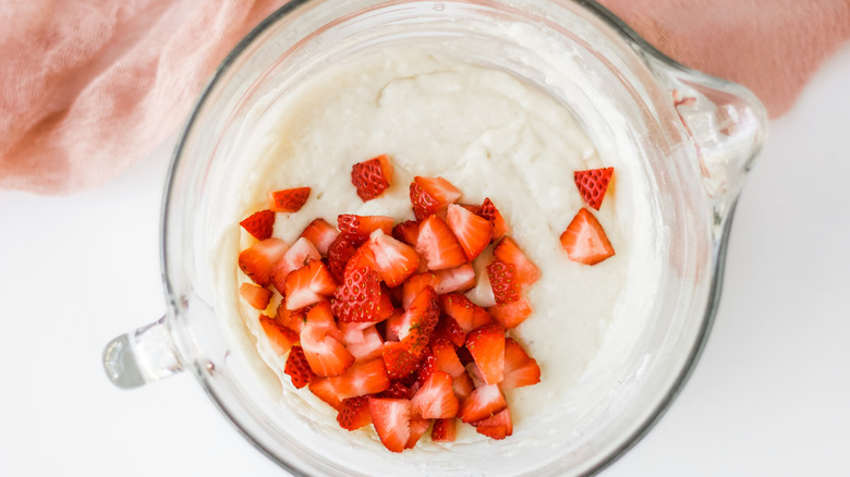 Overhead shot of pancake batter with chopped strawberries on top in a glass measuring cup